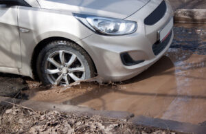 car on a mud pothole | pothole damage